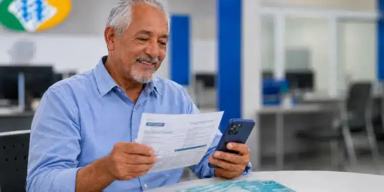 Aposentado consultando documento e celular em agência, representando o pagamento de atrasados do INSS.