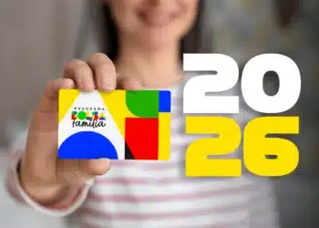 Mulher segurando o cartão do Programa Bolsa Família 2026, com destaque para o ano e as cores do logo.