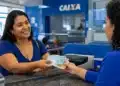 Mulher recebendo cédulas em uma agência da Caixa, representando o início dos pagamentos do Bolsa Família nesta segunda-feira, 20 de julho.