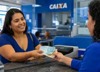 Mulher recebendo cédulas em uma agência da Caixa, representando o início dos pagamentos do Bolsa Família nesta segunda-feira, 20 de julho.