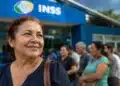 Mulher em frente a uma agência do INSS enquanto aguarda atendimento, representando a queda na fila de benefícios.