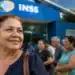 Mulher em frente a uma agência do INSS enquanto aguarda atendimento, representando a queda na fila de benefícios.