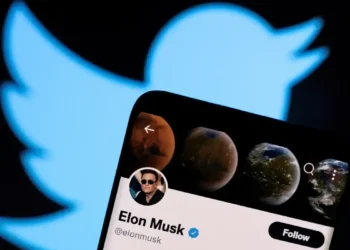 Perfil de Elon Musk aberto no Twitter em um smartphone, com o logotipo da plataforma ao fundo