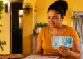 Mulher segura notas de R$ 100 ao lado de calendário de setembro, em referência às datas de pagamento do Bolsa Família.
