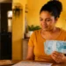 Mulher segura notas de R$ 100 ao lado de calendário de setembro, em referência às datas de pagamento do Bolsa Família.