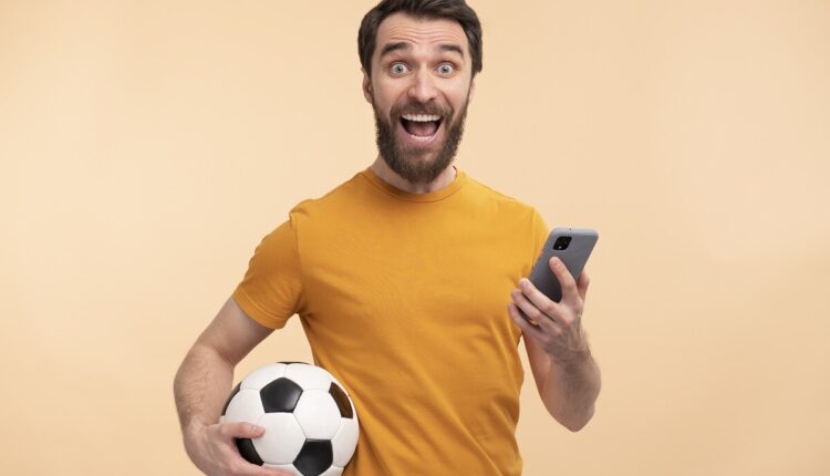 Fã de futebol brasileiro adulto usando smartphone de bandeira assistindo  jogo pelo celular streaming online