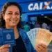 Mulher segura carteira de trabalho e notas de real em frente a uma agência da Caixa, representando a solicitação do Saque Calamidade do FGTS.