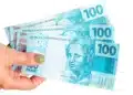 Mão segurando três notas de R$ 100 para representar o pagamento de agosto do Mães de Pernambuco