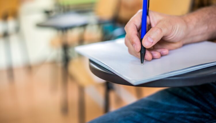 A man is writing/signing on a paper Focused on a hand with pen