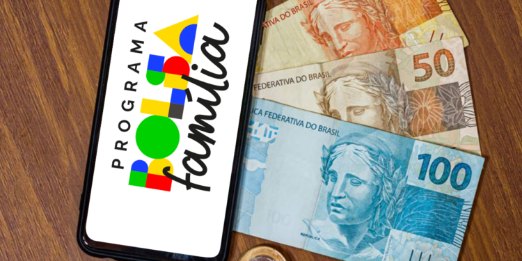 Celular exibindo o logo do programa Bolsa Família, com notas de 20, 50 e 100 reais e moedas ao fundo