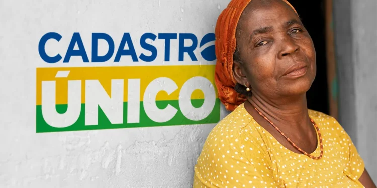 Mulher usando blusa amarela junto a uma parede escrito "Cadastro único"