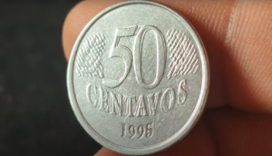 Moeda de 50 centavos de 1995 com erro de cunho duplicado, mostrando detalhes do reverso com sobreposição do valor e inscrições.