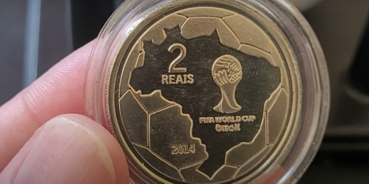 Reverso da moeda de 2 reais comemorativa da Copa do Mundo de 2014, com mapa do Brasil e taça da FIFA.