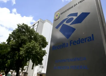 Placa da Receita Federal com o nome e logo visíveis em frente a um edifício público, em Brasília