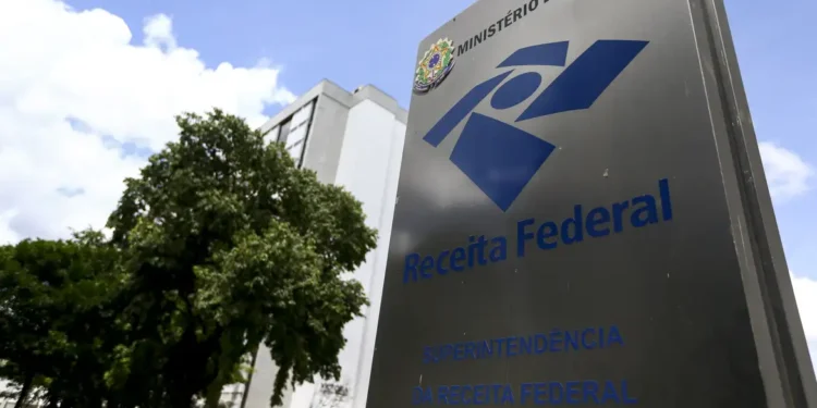 Placa da Receita Federal com o nome e logo visíveis em frente a um edifício público, em Brasília