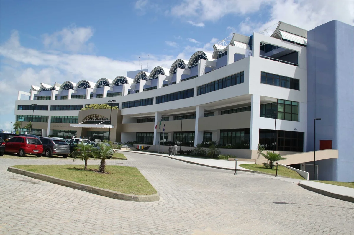 Imagem do prédio do Ministério Público da Bahia com fachada moderna e estacionamento na frente