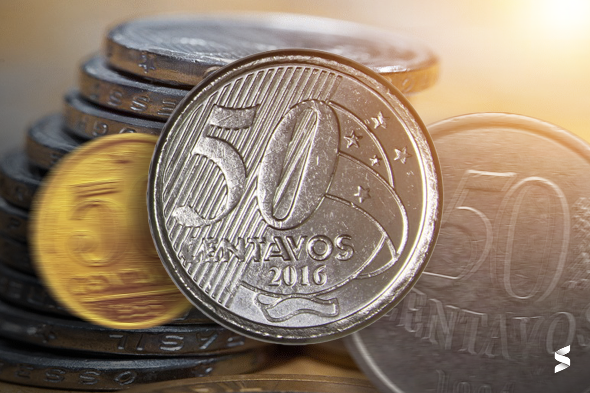 Moeda de 50 centavos com detalhes visíveis e outras moedas ao fundo.