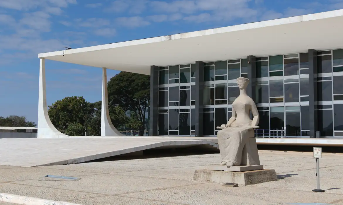 Vista do prédio do STF com a escultura de uma figura feminina, representando a justiça, ao fundo.