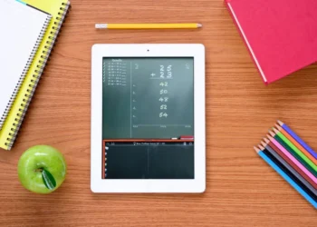 Tablet com aplicativo de matemática exibindo cálculos, rodeado por materiais escolares