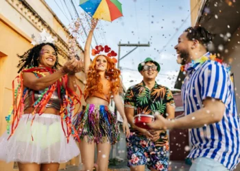 Grupo de pessoas fantasiadas se divertindo no Carnaval, jogando confete e comemorando na rua