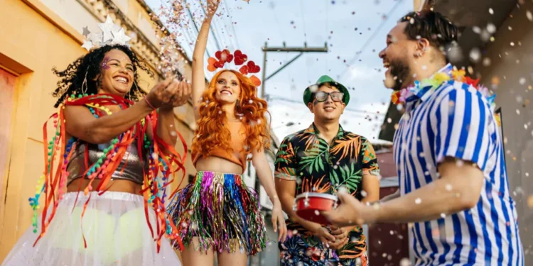 Grupo de pessoas fantasiadas se divertindo no Carnaval, jogando confete e comemorando na rua