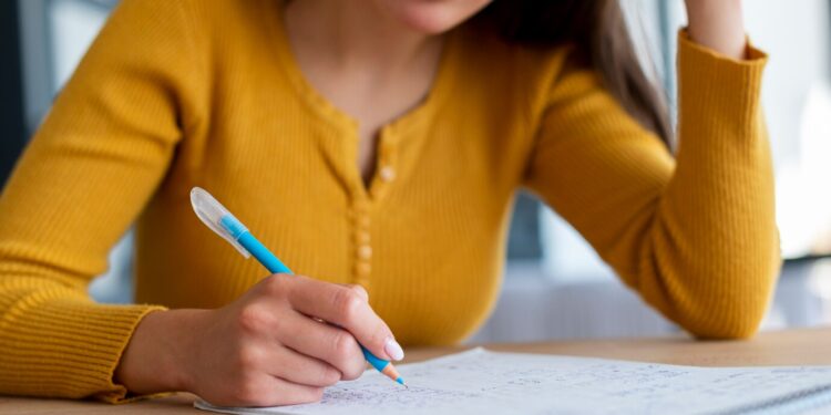 Estudante concentrada escrevendo em caderno, representando preparação para o concurso da Unespar.