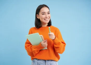 Pessoa sorrindo com caderno e caneta, pronta para inscrição no concurso SEFAZ RJ