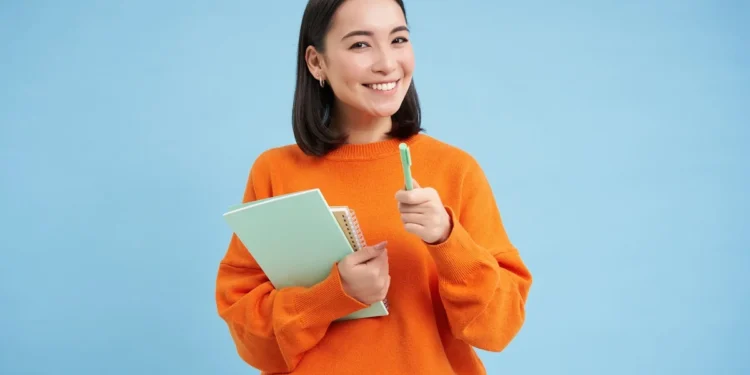 Pessoa sorrindo com caderno e caneta, pronta para inscrição no concurso SEFAZ RJ