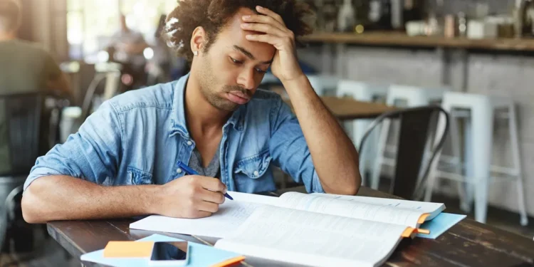 Pessoa com expressão de cansaço e dificuldade durante os últimos momentos de estudo antes do encerramento das inscrições para o concurso e seleção da Prefeitura.