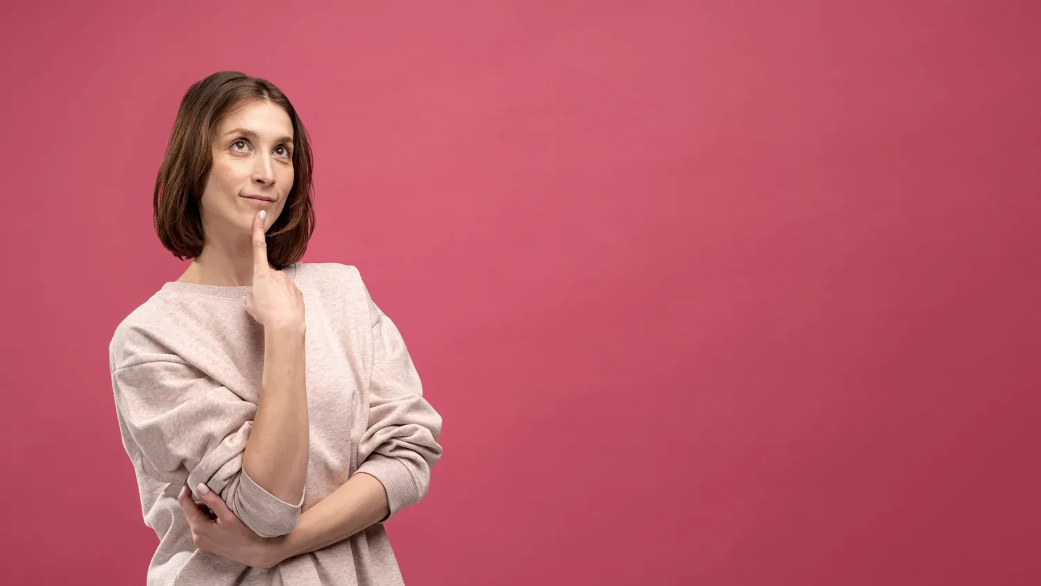 Mulher pensativa com expressão de dúvida sobre fundo rosa