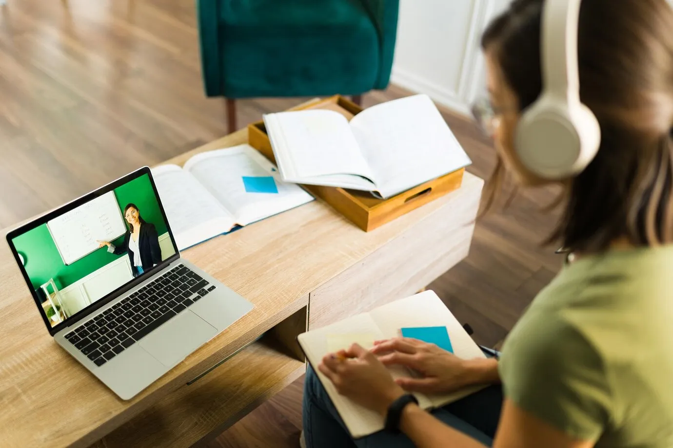 Estudante assistindo a uma aula online enquanto faz anotações para concursos públicos.