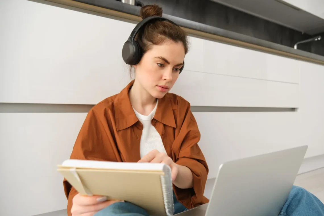 Mulher estudando com fones de ouvido e notebook, utilizando tecnologia para otimizar o aprendizado