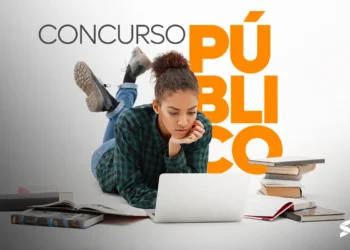 Mulher jovem estudando para concurso público com notebook e livros ao redor