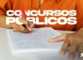 Pessoa estudando para concursos públicos, escrevendo em um caderno com caneta vermelha