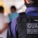 Guarda Municipal de costas, vestindo uniforme e colete tático com a inscrição "Guarda Municipal"