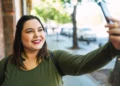 Mulher sorrindo e tirando uma selfie, representando o alerta sobre o golpe da selfie