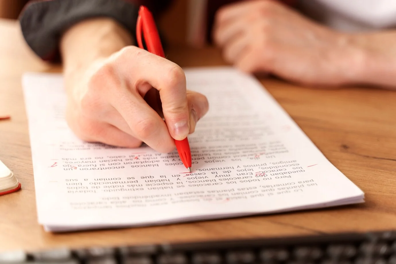 Pessoa corrigindo um formulário com caneta vermelha, representando o processo de inscrição para o concurso da Prefeitura de Normandia.