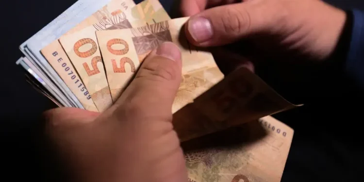 Pessoa segurando notas de R$ 50, representando o valor dos prêmios da Loteria dos Sonhos