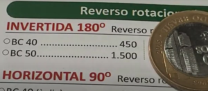 Moeda de 1 real BC 50 anos com erro de reverso invertido, junto ao catálogo mostrando seu valor.