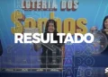 Mulher exibindo o resultado da Loteria dos Sonhos ao vivo, com bolas e sorteio