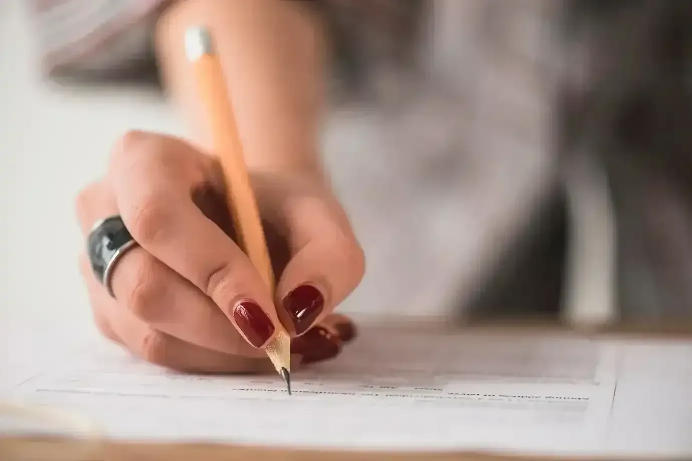 Pessoa preenchendo formulário com lápis, simbolizando a participação no concurso da Prefeitura de Quixeramobim.