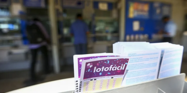 Volantes da Lotofácil em destaque dentro de uma lotérica, com clientes ao fundo