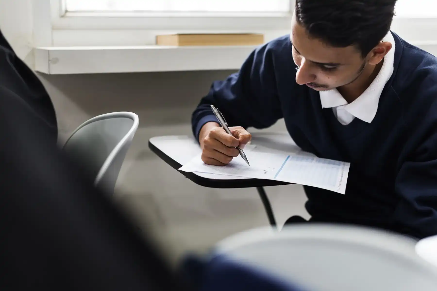 Jovem prestando atenção durante a prova de concurso, simbolizando a inscrição para o concurso da Prefeitura de Itumbiara.