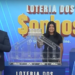 Apresentador anuncia os números da Loteria dos Sonhos de sexta-feira (14/03), com assistentes ao fundo realizando o sorteio