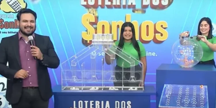 Apresentadores do sorteio da Loteria dos Sonhos, com um globo de números e uma casa transparente