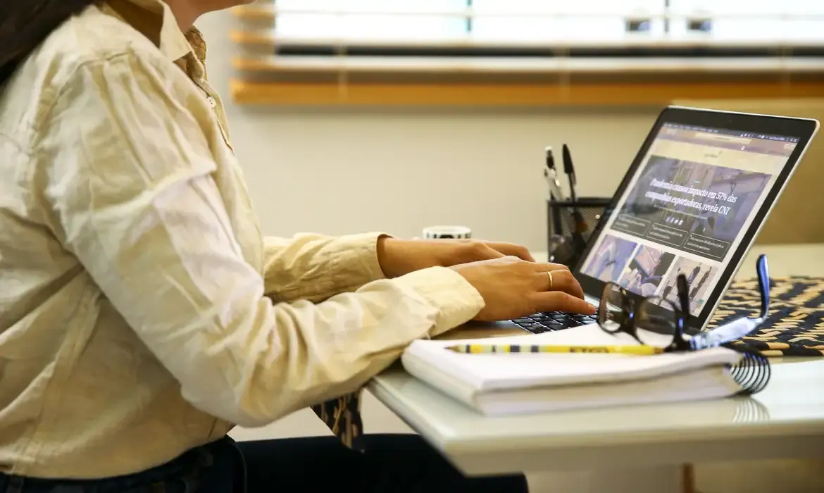 Pessoa digitando em um notebook enquanto procura sobre as profissões com maiores salários.