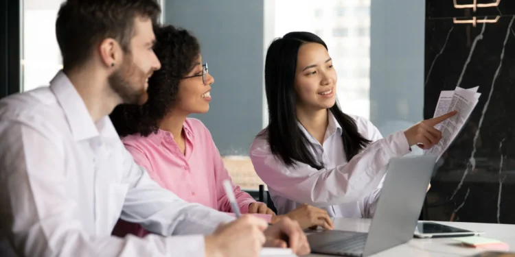 Equipe de trabalho colaborando em uma reunião, analisando documentos e discutindo ideias em um ambiente corporativo moderno