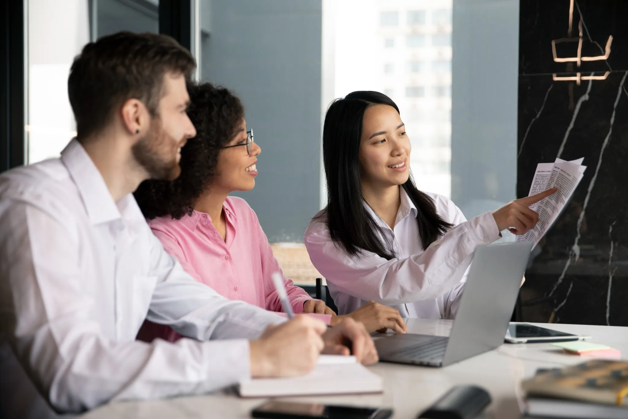 Equipe de trabalho colaborando em uma reunião, analisando documentos e discutindo ideias em um ambiente corporativo moderno