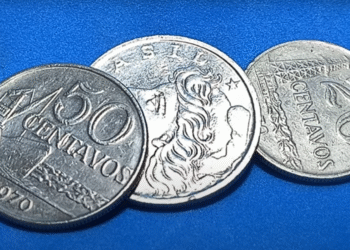 Três moedas brasileiras de 1970, incluindo as de 20 e 50 centavos, sobre fundo azul