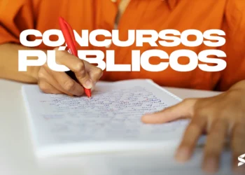 "Pessoa escrevendo sobre concurso público com caneta vermelha em um caderno, com foco em 'Concursos Públicos'."
